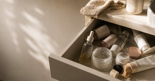 A woman looking thoughtfully at skincare products on a bathroom shelf, representing the frustration of products that don't deliver results